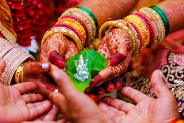 groom and bride holding green leaf and lord Ganesha sculpture in hand