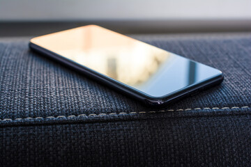 Business Smartphone With Reflection Lying On The Armrest Of A Couch
