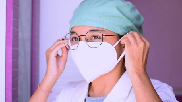 Portrait of young Indian female surgeon doctor in hospital wearing N95 mask and giving thumbs up during corona virus pandemic in 2021
