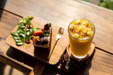Iced fresh mango smoothies glass and Fruit cake decorated with figs on plate wooden