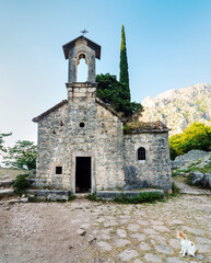 Fototapeta na wymiar Church of Saint John and ancient courtyard,surrounded by beautiful rocky mountain scenery at sunset, Kotor,Montenegro.