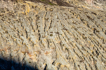 Mountain furrows wave surface pattern from lava flow at the top of Ijen volcano crater.Beautiful Landscape mountain and green lake with smoke sulfur in a Kawah Ijen volcano.East Java, Indonesia