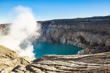 Ijen volcano crater with lake and sulphur mining. Beautiful Landscape mountain and green lake with smoke sulfur in the morning in a Kawah Ijen volcano. Beautiful landmark from East Java, Indonesia