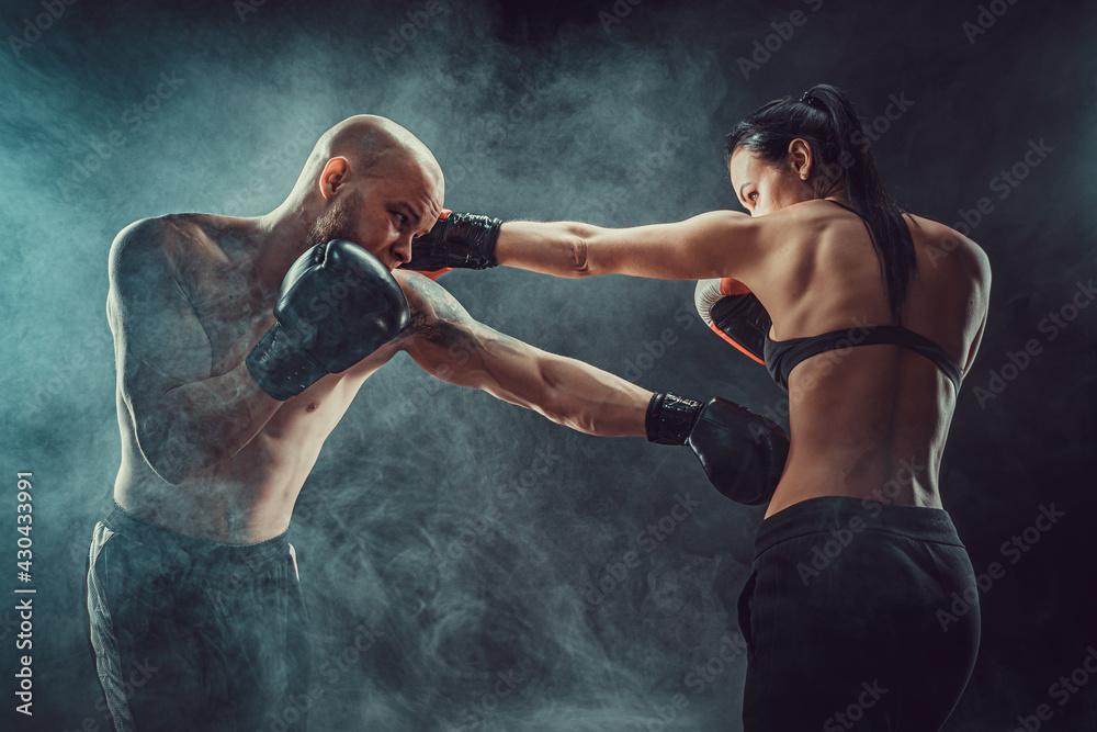 Wall mural Shirtless Woman exercising with trainer at boxing and self defen