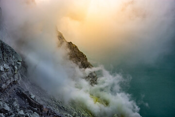 Ijen volcano crater with lake and sulphur mining. Beautiful Landscape mountain and green lake with smoke sulfur in the morning in a Kawah Ijen volcano. Beautiful landmark from East Java, Indonesia
