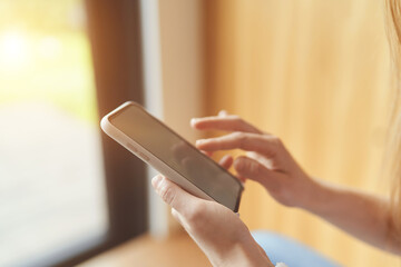 Side view of mockup image of a woman holding a smartphone with blank white desktop screen