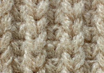 The background is made of natural fabric with a pattern. Beige knit. Fine texture of the fabric. Suitable for your text or logo. Macro. Copy space. From above.