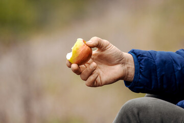 Woman holding a piece of apple in her hand. Woman eating an apple