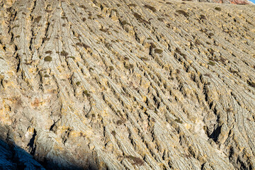 Mountain furrows wave surface pattern from lava flow at the top of Ijen volcano crater.Beautiful Landscape mountain and green lake with smoke sulfur in a Kawah Ijen volcano.East Java, Indonesia