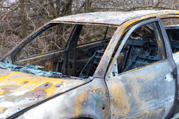 Burned car after an accident on the asphalt road. Close-up, fragment. Arson of a car, criminal...