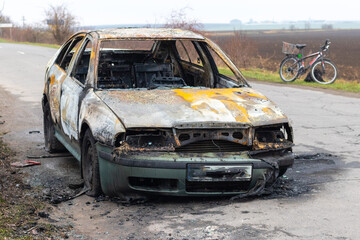 Burned car after an accident on the asphalt road. Front view. Arson of a car, criminal showdowns