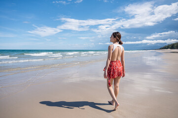 Attractive young asian woman in swimwear walking on the beach at tropical sea in sunny day