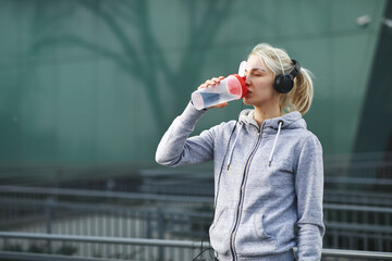 Young woman resting after jogging and drinking water in the city
