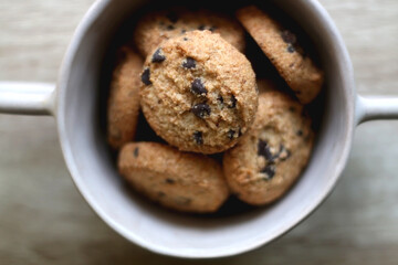 Bowl of chocolate chip cookies on wooden table. Flat lay.