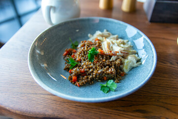 Delicious buckwheat porridge with sauce and parsley in a blue plate