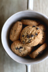 Bowl of chocolate chip cookies on wooden table. Flat lay.