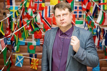 adult man with glasses in his hand against the background of the country flag