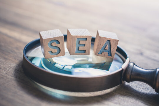 Vintage Magnifier With SEA Blocks On An Old Wooden Table - Search Engine Advertising Concept