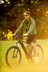 Fototapeta premium Young man riding ebike in the park