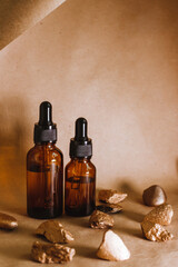 Cosmetic oil in a container with a pipette stands among the stones. Essential oil for aromatherapy.