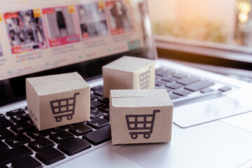 Online shopping. Credit card and cardboard box with a shopping cart logo on laptop keyboard. Shopping service on The online web. offers home delivery.