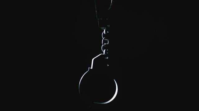 The police is giving the handcuff to a prisoner. Detention of a suspect. Red and blue light from a police flashers.