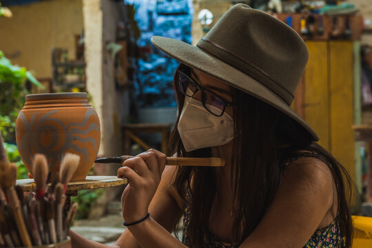 Adventurous tourist girl, learning to paint crafts in a pottery and clay workshop.