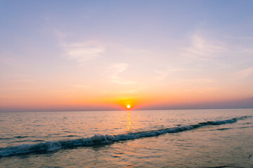 Obraz premium Sunset reflection sea. beautiful sunset behind the clouds and blue sky above the over sea landscape background