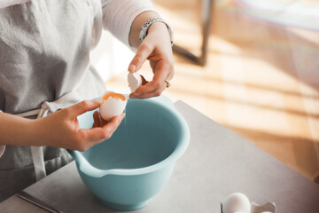 Girl breaks an egg into a bowl for baking. culinary cover