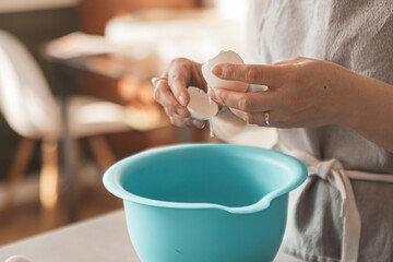 Girl breaks an egg into a bowl for baking. culinary cover