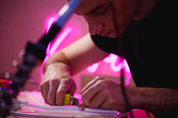 Cropped view of craftsman with stationery knife working with flex neon 