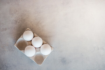 White eggs in a stand are on a gray concrete table. Cooking, food, ingredients