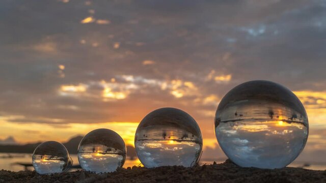like there are four worlds arranged by size..time lapse four crystal balls placed on the beach can see the inverted reflection of the sea view in the sunset..A 4K video for a uniquetravel idea.