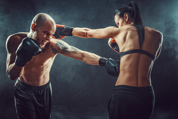 Fototapeta na wymiar Shirtless Woman exercising with trainer at boxing and self defen