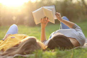 Beautiful girl lies on meadow and reads the book