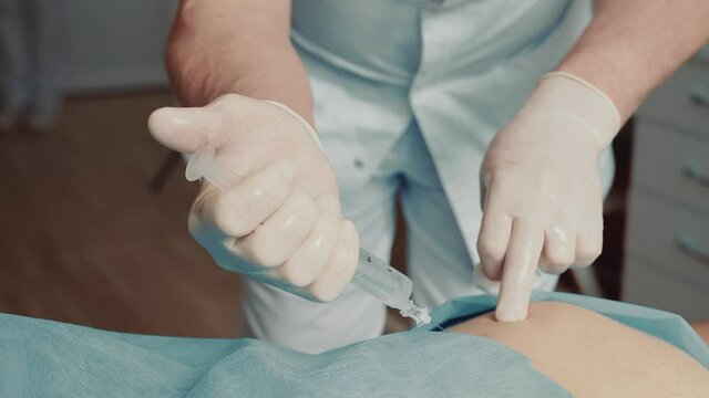 Orthopedist-traumatologist making an injection with a large needle in the patient's buttocks. Deep injection blockade.