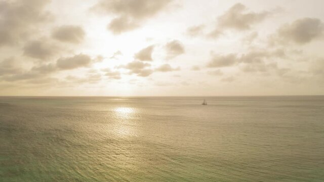 aerial image with sunset drone at eagle beach with catamarans on the horizon in aruba in the caribbean