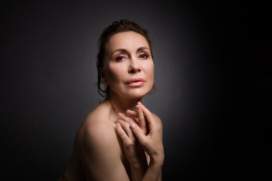 portrait of a sensual fifty year old woman on grey studio background