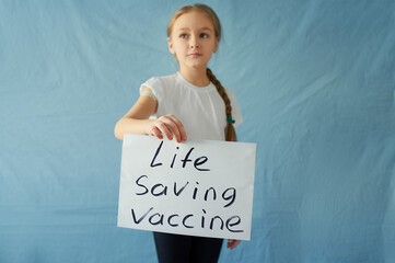 A little girl holds a placard with the words "life will be saved by a vaccine" looking away. Teen on a blue background