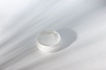 White opening of a jar of cosmetic products. Plastic container with cream, lotion, face mask. The concept of environmentally friendly, organic cosmetology.