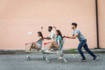 Young happy friends running with shopping carts