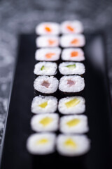 set of sushi rolls with seafood on a black stone background