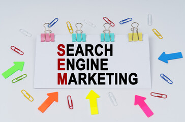 On the table there are paper clips and directional arrows, a sign that says - Search Engine Marketing