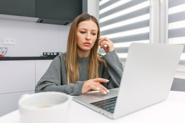 Work from home. A young girl looks into the laptop screen. E-learning. Distance learning.