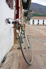 Fototapeta na wymiar Old bicycle parked on a wall with a Spanish colonial house in the background.