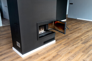 Open, dirty corner pane in a modern fireplace with a closed combustion chamber standing in the...