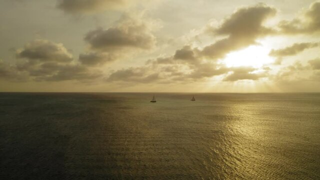 aerial image with sunset drone at eagle beach with catamarans on the horizon in aruba in the caribbean