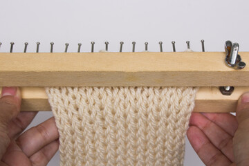 Homemade knitting loom made with wood . In process of knitting wool scarf, warm soft winter...