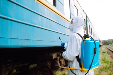 Man wearing protective suit disinfecting public a train with spray chemicals to preventing the spread of coronavirus, pandemic in quarantine city. Covid -19. Cleaning concept.