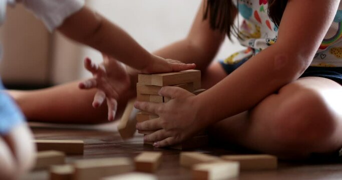 Sibling destroying sister building blocks. Little girl protecting blocks